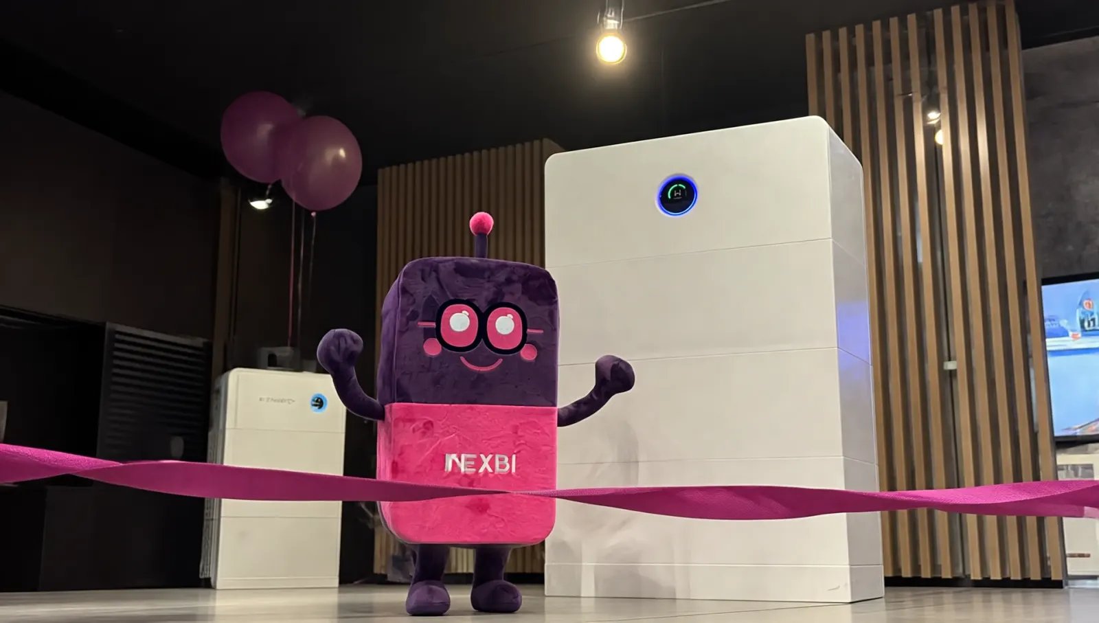 Maskotka NEXBI w showroomie NEXBE obok magazynów energii